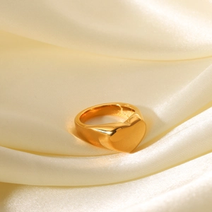 Polished 18K gold plated stainless steel heart ring on elegant white silk fabric