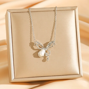 Sparkling butterfly pearl necklace displayed on a golden gift box with silk background
