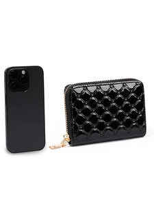 Quilted patent leather wallet in black with gold zipper next to a phone for scale
