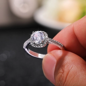 Macro shot of silver halo ring featuring round center stone and pavé diamond band