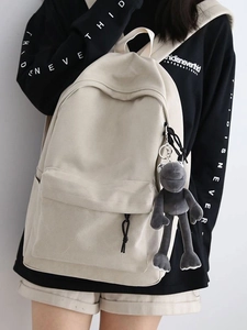 Minimalist beige canvas backpack for school or travel featuring large capacity and a charm
