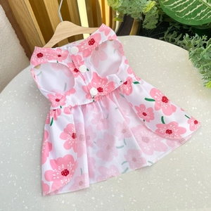 Detailed view of a pink floral pet summer dress with white buttons on a wooden hanger