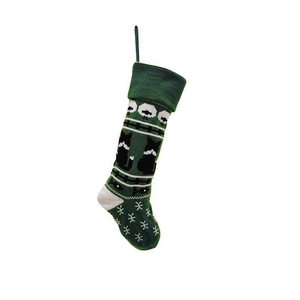 Detail of green knit Christmas stocking featuring white cat, fishbone and snowflake patterns