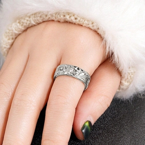 Detailed macro shot of vintage silver ring with floral relief patterns on a finger