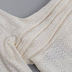 Détail du tissu en dentelle blanc cassé avec motifs floraux au crochet et maille texturée