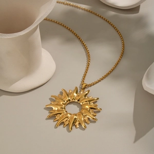 Macro shot of gold sun pendant necklace with polished finish on a stone surface