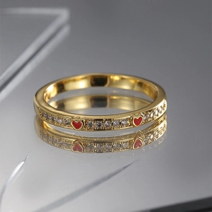 Close-up of gold-plated ring with red enamel hearts and sparkling white zircon stones