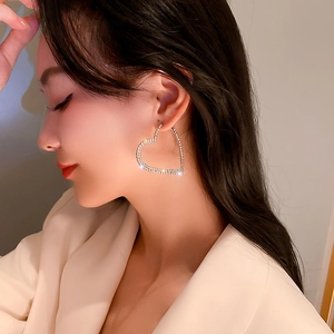 Gros plan d'un mannequin portant de grandes créoles cœur en argent avec des strass brillants