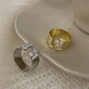 Three-layer zircon open rings in gold and silver finish on a ceramic dish