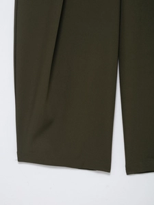 Detailed view of dark olive green woven pants hem with flat lockstitch craftsmanship