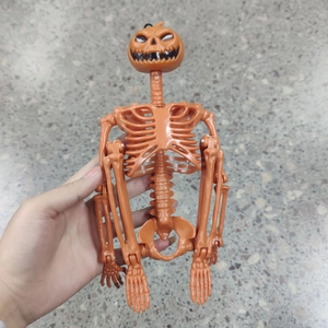 Detail of a movable Halloween orange pumpkin head skeleton prop held over a stone floor