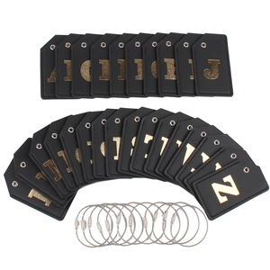 Close-up of black faux leather luggage tags with gold metal letters and steel wire loops