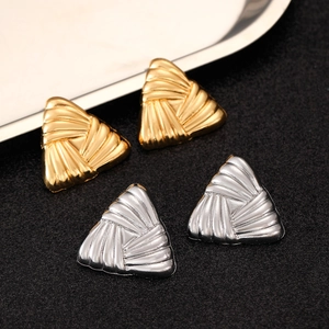 Macro shot of gold and silver irregular triangle earrings with textured metallic surface