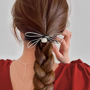 Silver bow hair claw clip with heart charm worn on braided hair, detailed back view