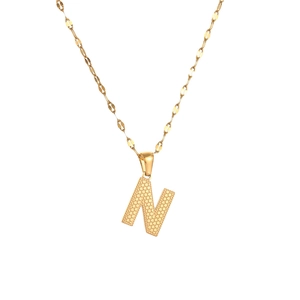Macro detail of gold letter N pendant featuring unique dotted texture on a fine chain