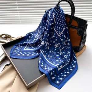 Detailed texture of blue silk scarf with white polka dots and elegant floral patterns