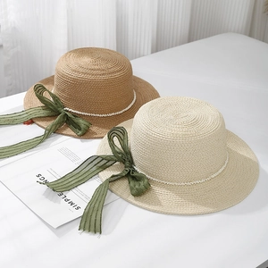 Flat top straw hat with green ribbon bow and pearls for sun protection and vacation