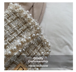 Close-up of the elegant bouclé tweed texture with pearl trim and gold metal lock