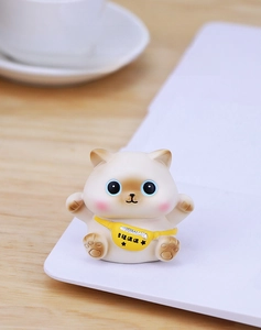 Close-up of cute white resin lucky cat figurine with blue eyes and yellow crossbody bag