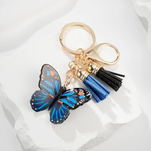 Blue butterfly keychain with black suede tassels and golden keyring on white stone