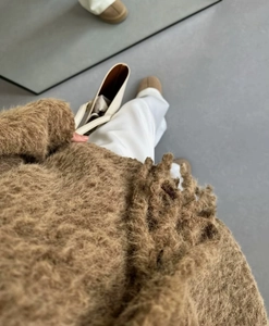 Close-up of brown plush fuzzy knit sweater paired with white trousers and tote bag