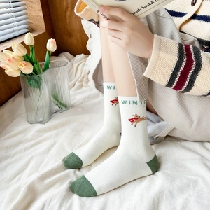 Detail of white winter socks with green trim and cute elk embroidery in a cozy room
