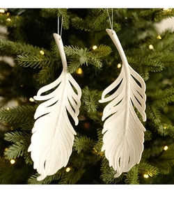 Close-up of white feather-shaped Christmas tree ornaments with subtle glitter on pine branch