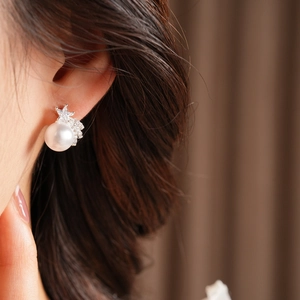 Gros plan d'une boucle d'oreille étoile avec perle et zircons portée par un mannequin sur tissu