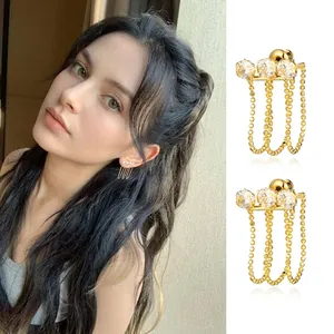 Detail of gold tassel earrings with three clear zircons and long metallic bead chains