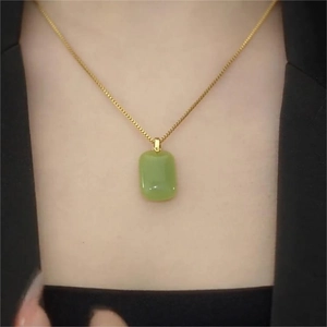 Close-up of a green jade-style pendant necklace on a model with a gold chain