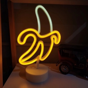 Close-up of yellow banana neon sign glowing on a white base for desktop decoration