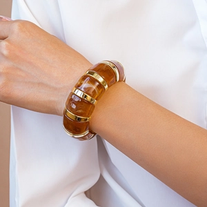 Chic amber resin cuff with gold metal bands worn over a white shirt sleeve
