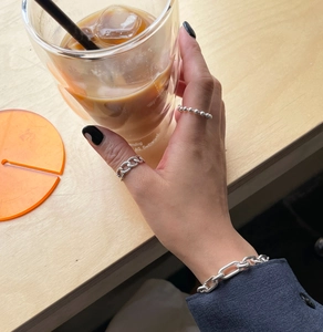 Close-up of a 925 sterling silver bead ring and chain bracelet set on a person's hand