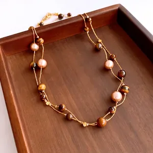 Double-layered tiger eye and pearl bead necklace with gold chain in a wooden tray