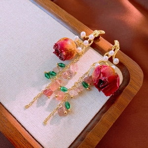 Detail of floral earrings with preserved red roses, pearls and strawberry crystals