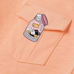 Cute pink anti-depressant cat bottle enamel pin accessory on a shirt pocket