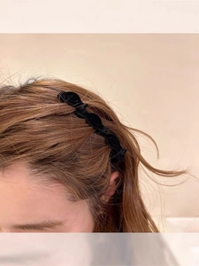 Detail of wavy black flocked hair clip worn on side bangs for a textured hairstyle