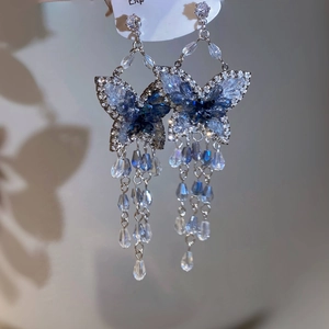 Detail von Silbernadel-Ohrringen mit blauem Kristall-Schmetterling und langen Quasten