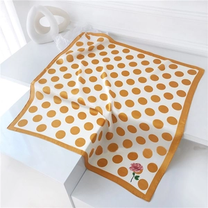 Detail of polka dot silk scarf with pink rose print on white tiered display stand