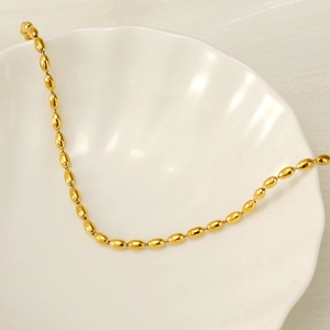 18k vergoldete Edelstahlhalskette mit Ovalperlen auf einem weißen Muschelteller