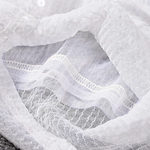 Détail macro du tissu en maille blanche avec paillettes délicates et surpiqûres