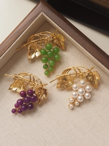Detail of vintage grape brooches with jade, purple beads and pearls in a wooden tray