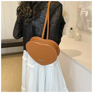 Rear view of model wearing a vintage brown heart-shaped shoulder bag with slim straps