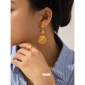 Detailed view of 18K gold plated shell drop earrings and starfish ring on model