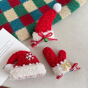 Three-piece Christmas hair clip set with red felt hats and gloves on a cozy background