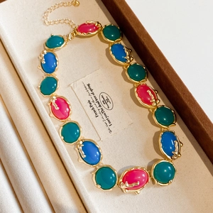 Détail du collier français vintage en résine avec pierres colorées et bords dorés