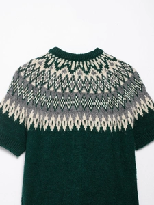 Detail of dark green knit sweater featuring white Fair Isle geometric jacquard patterns