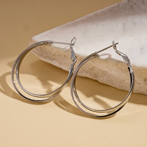 Vue détaillée de boucles d'oreilles doubles créoles argentées polies sur pierre blanche