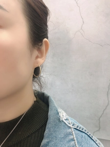 Close-up of minimalist gold hoop earrings worn by model with denim jacket and green knitwear
