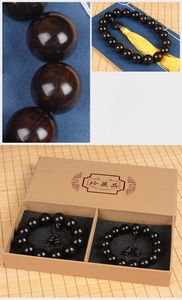 Macro shot of dark ebony prayer beads with natural wood grain and yellow tassel in a gift box